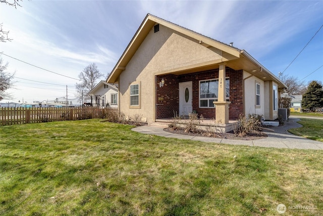 exterior space with stucco siding, a front lawn, central AC, fence, and brick siding