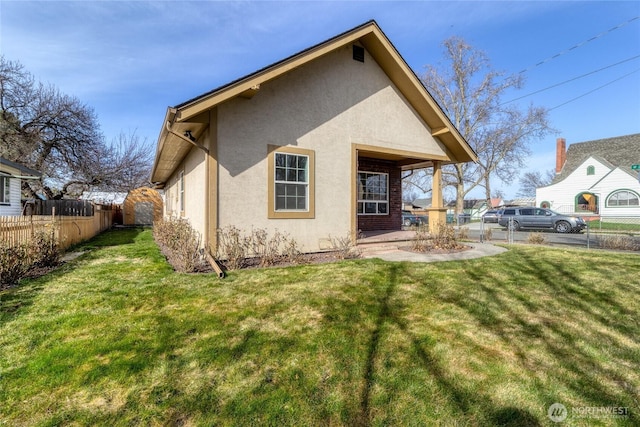 rear view of property featuring stucco siding, a yard, and fence