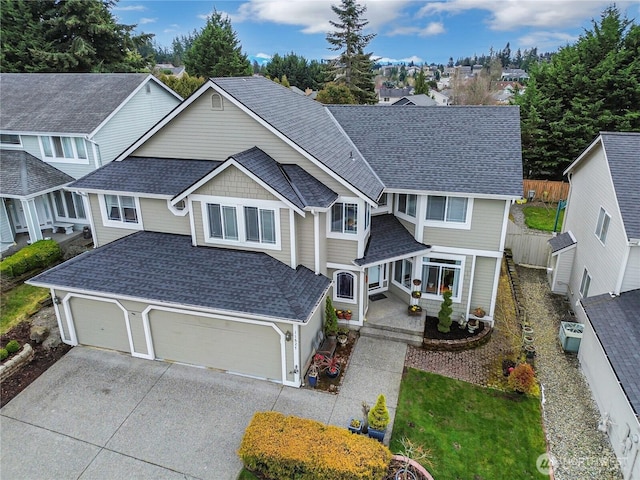 view of front of home with driveway, fence, a residential view, roof with shingles, and a garage