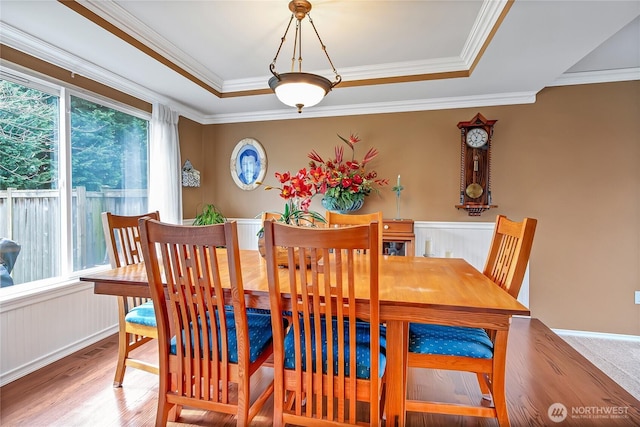 dining room featuring a raised ceiling, wood finished floors, and crown molding