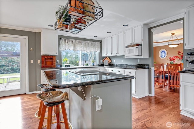 kitchen with white microwave, crown molding, a wealth of natural light, and a sink