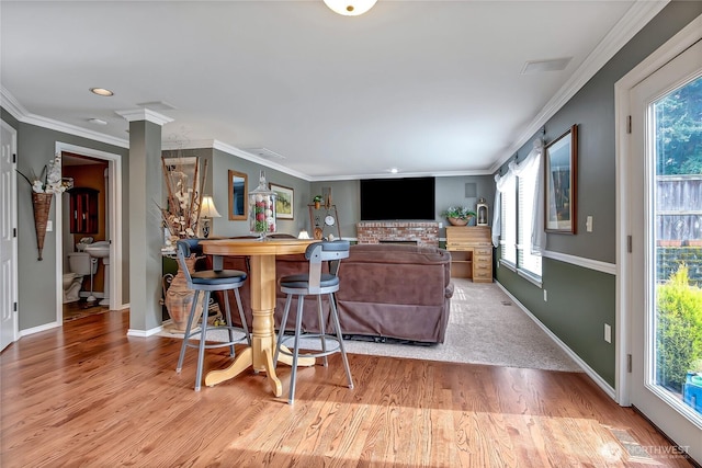 living area featuring baseboards, plenty of natural light, wood finished floors, and crown molding