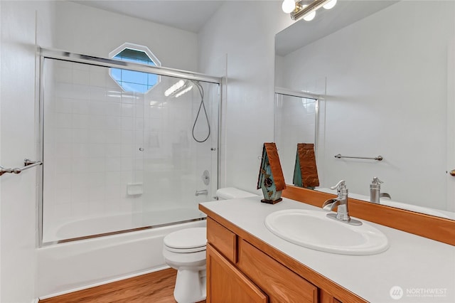 bathroom featuring vanity, toilet, wood finished floors, and combined bath / shower with glass door