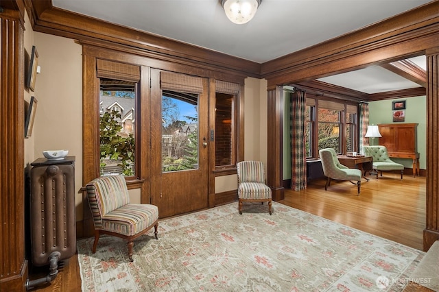 sitting room featuring wood finished floors, radiator heating unit, and ornamental molding