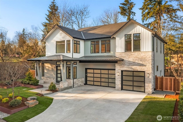 modern farmhouse with a standing seam roof, an attached garage, stone siding, and driveway