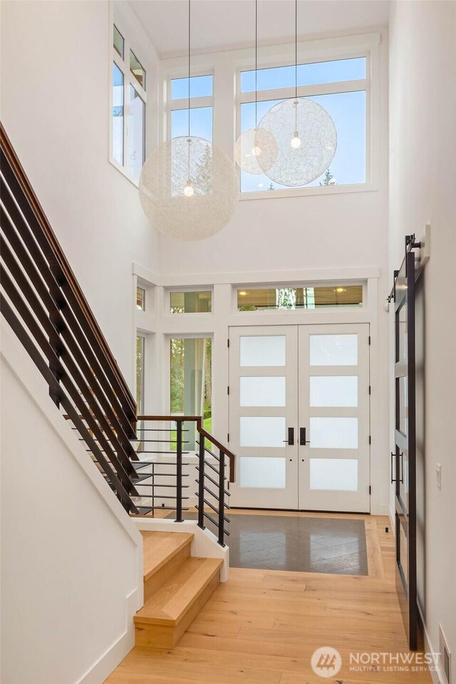 foyer entrance with a healthy amount of sunlight, french doors, stairs, and wood finished floors