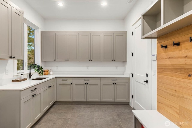 kitchen featuring gray cabinets, open shelves, and a sink