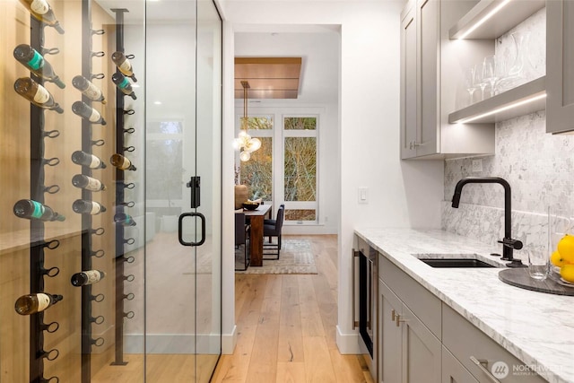 wine cellar with a sink, light wood-type flooring, and beverage cooler