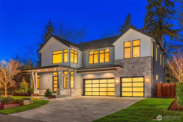 view of front facade featuring a garage, fence, stone siding, and driveway