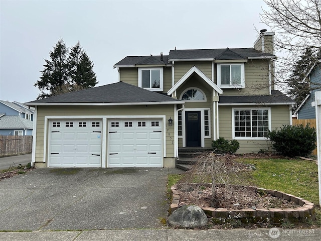 traditional-style house featuring a chimney, driveway, an attached garage, and fence