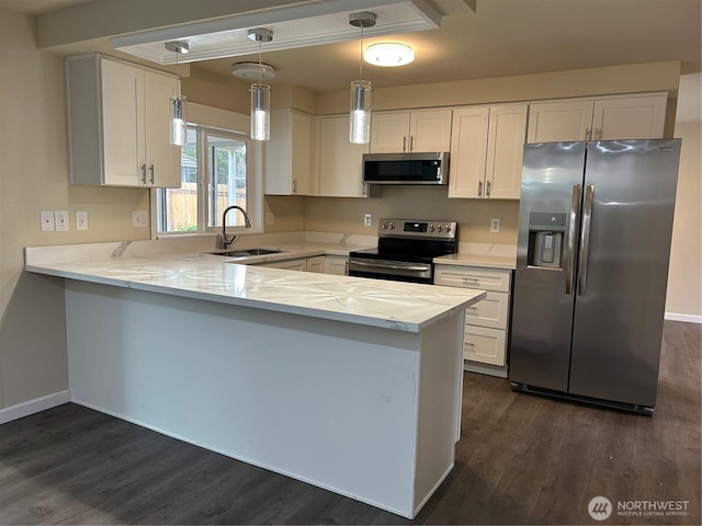 kitchen with a sink, a peninsula, stainless steel appliances, white cabinetry, and dark wood-style flooring