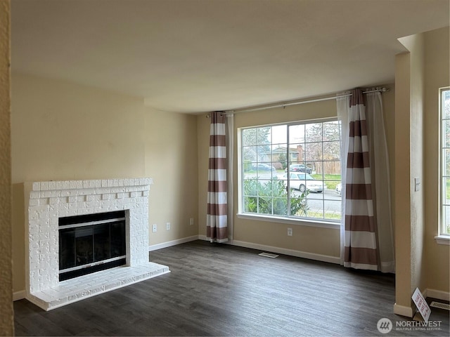 unfurnished living room featuring dark wood finished floors, visible vents, a fireplace, and baseboards