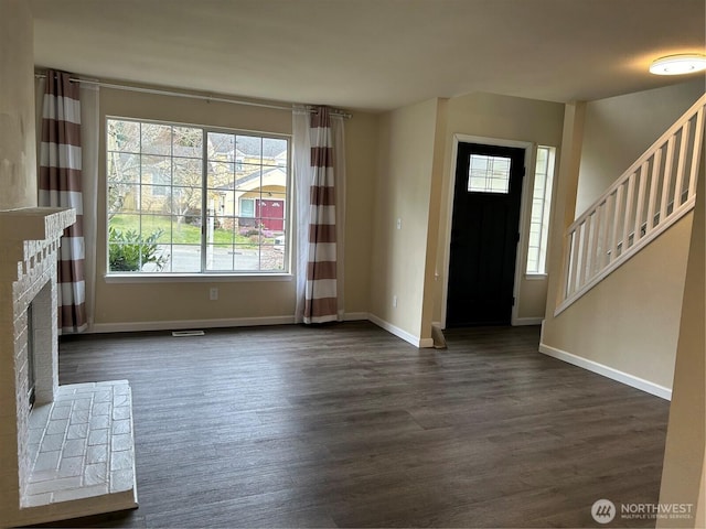 entryway with a brick fireplace, stairs, baseboards, and dark wood-style flooring