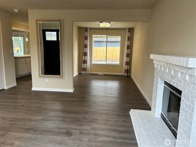 unfurnished living room featuring baseboards, dark wood-style flooring, and a fireplace