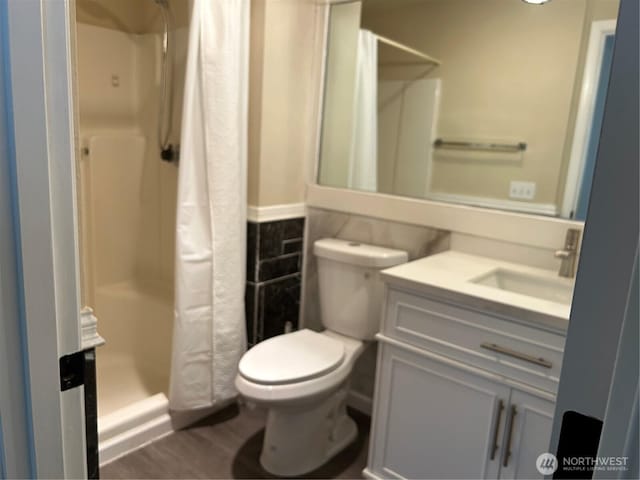 bathroom with a shower stall, vanity, toilet, and wood finished floors