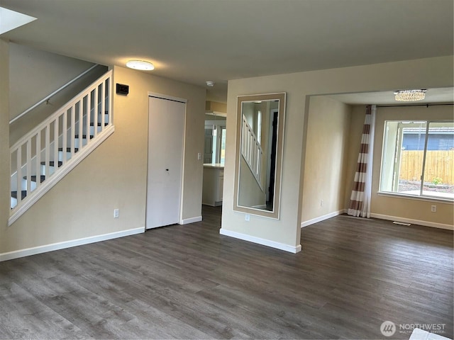 unfurnished living room with visible vents, stairway, dark wood-style floors, and baseboards