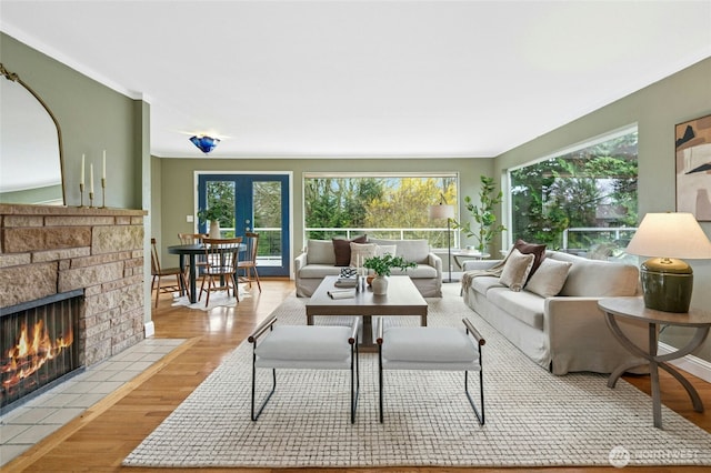 living area with a healthy amount of sunlight, a fireplace, french doors, and wood finished floors