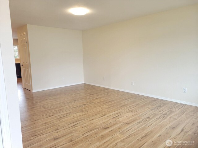 empty room with baseboards and light wood-type flooring