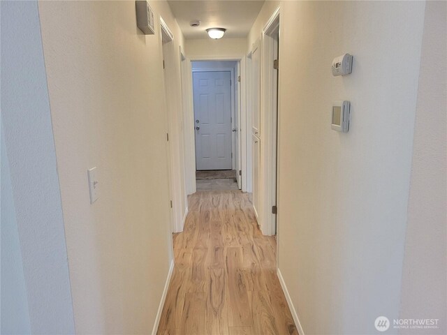 corridor featuring baseboards and light wood finished floors