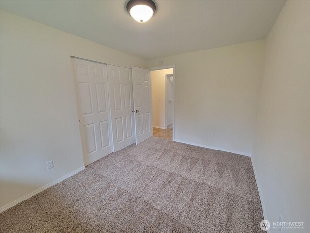 unfurnished bedroom with carpet, a closet, and baseboards