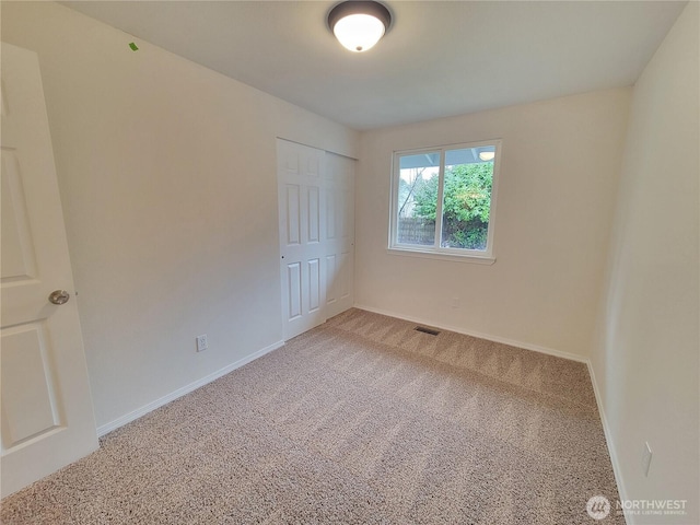 unfurnished bedroom with visible vents, baseboards, a closet, and light carpet