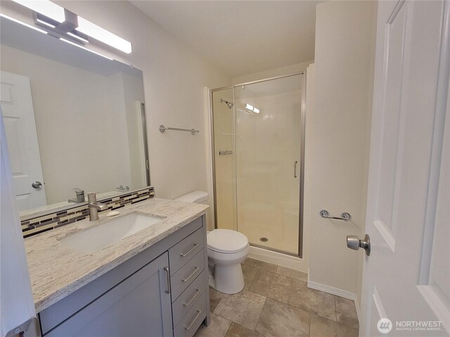 full bathroom featuring vanity, a shower stall, toilet, and tasteful backsplash