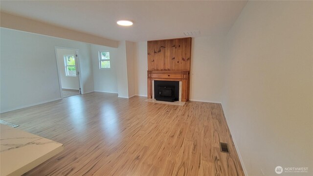 unfurnished living room featuring visible vents, a fireplace with flush hearth, and light wood-style floors