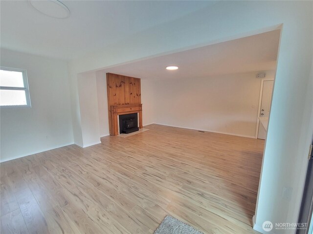 unfurnished living room featuring a fireplace, light wood-type flooring, and baseboards