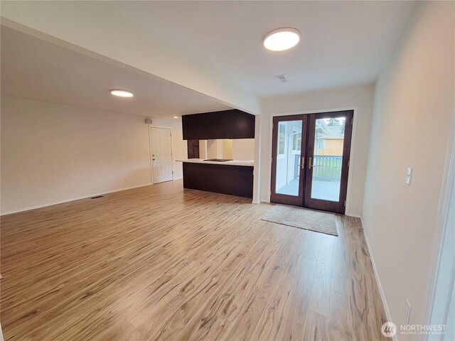 unfurnished living room with visible vents, french doors, baseboards, and light wood-style floors