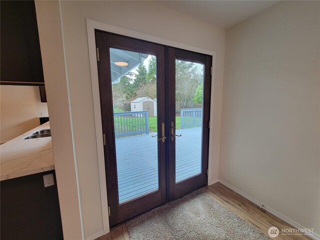 doorway with french doors, baseboards, and light wood finished floors