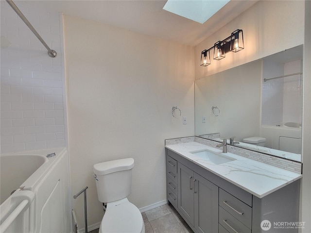 full bathroom featuring toilet, a skylight, vanity, and baseboards