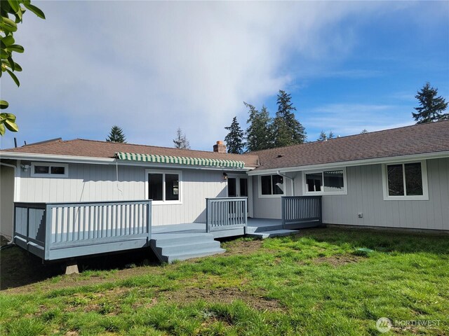 back of house with a yard, a wooden deck, and a chimney