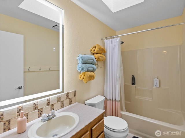 bathroom with vanity, a skylight, shower / tub combo, toilet, and backsplash