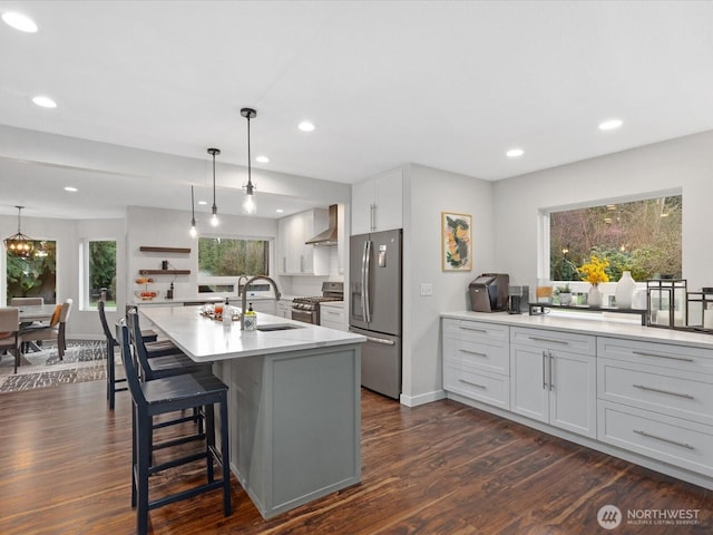 kitchen featuring a sink, recessed lighting, appliances with stainless steel finishes, wall chimney range hood, and dark wood-style flooring