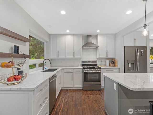 kitchen with dark wood-style floors, a sink, decorative backsplash, stainless steel appliances, and wall chimney range hood