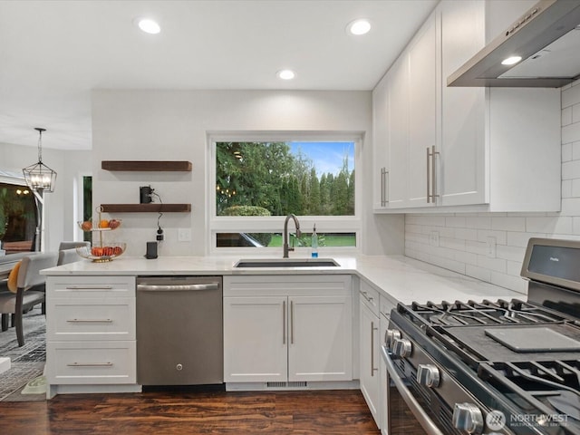 kitchen featuring light stone countertops, a sink, stainless steel appliances, under cabinet range hood, and backsplash