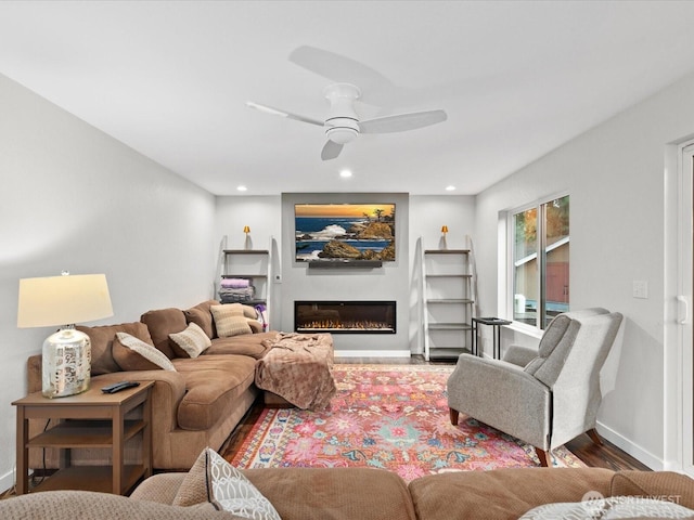 living area featuring baseboards, ceiling fan, recessed lighting, wood finished floors, and a glass covered fireplace