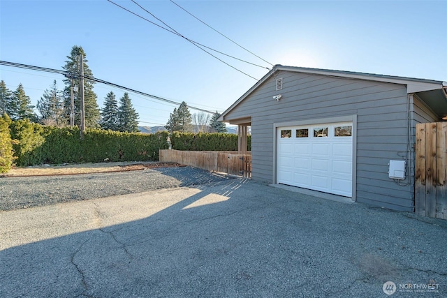 garage with aphalt driveway and fence