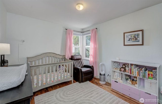 bedroom with a nursery area and wood finished floors