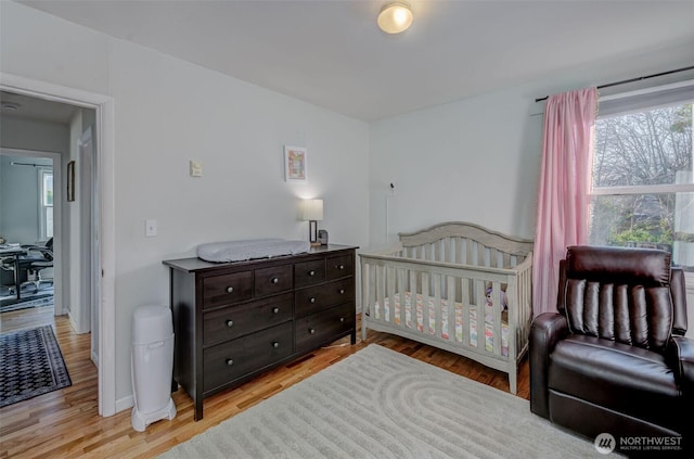 bedroom with a crib and light wood-style flooring