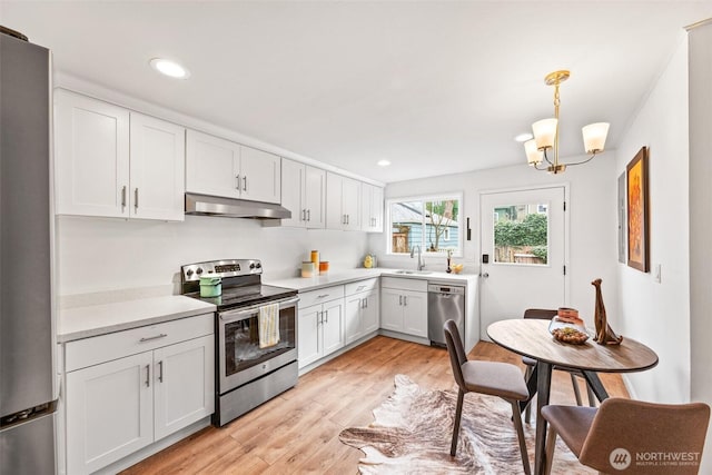 kitchen with light wood-style flooring, under cabinet range hood, appliances with stainless steel finishes, white cabinets, and light countertops