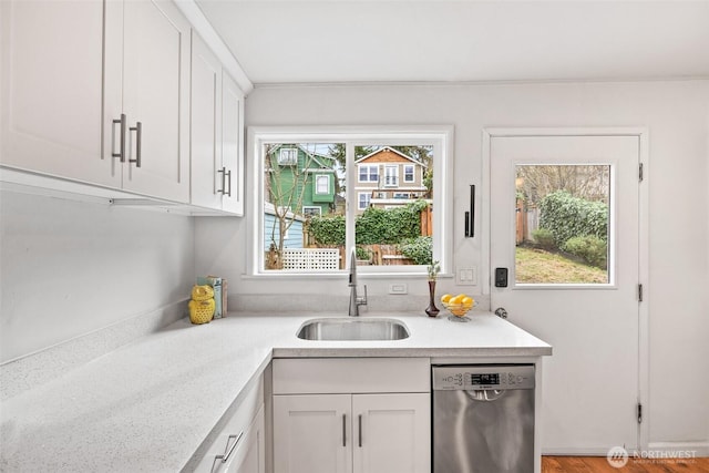 kitchen featuring a sink, stainless steel dishwasher, white cabinets, and light countertops