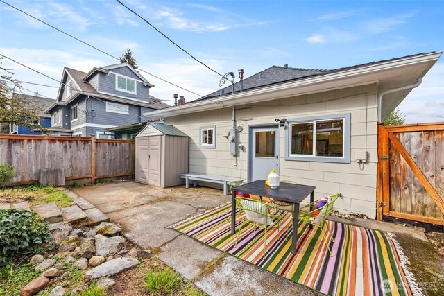 rear view of house featuring a patio, a storage shed, an outbuilding, and fence