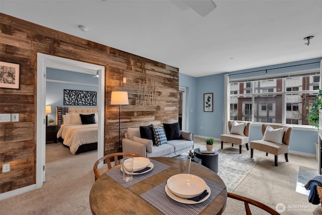 living room with wooden walls, baseboards, and light carpet