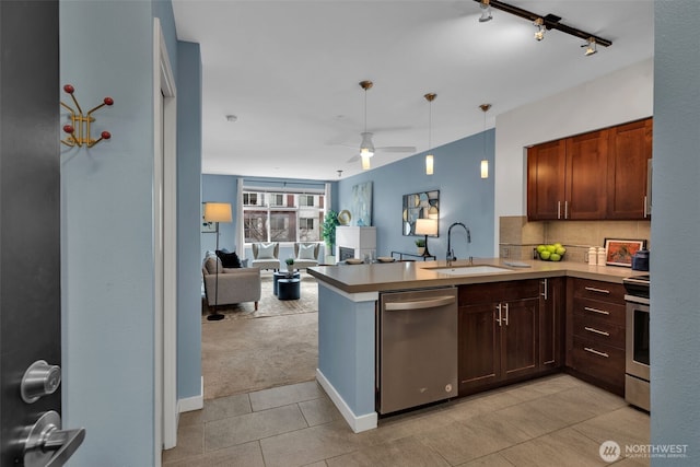 kitchen with a peninsula, a sink, decorative backsplash, stainless steel appliances, and open floor plan