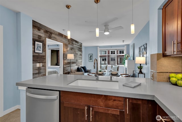 kitchen with tasteful backsplash, decorative light fixtures, open floor plan, stainless steel dishwasher, and a sink