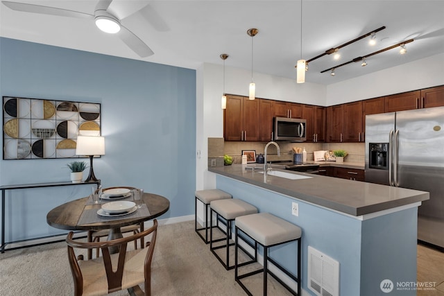 kitchen featuring visible vents, backsplash, a peninsula, a kitchen breakfast bar, and stainless steel appliances