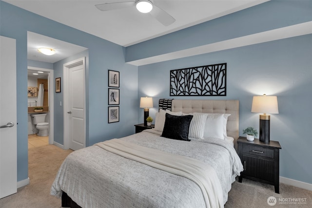 carpeted bedroom with ensuite bath, baseboards, and ceiling fan