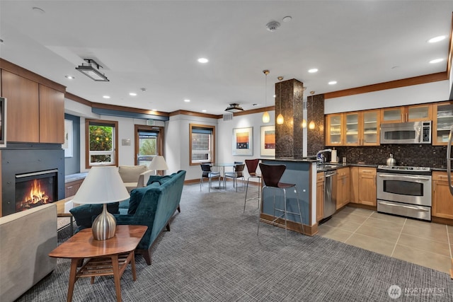 kitchen featuring a peninsula, a fireplace, appliances with stainless steel finishes, dark countertops, and open floor plan