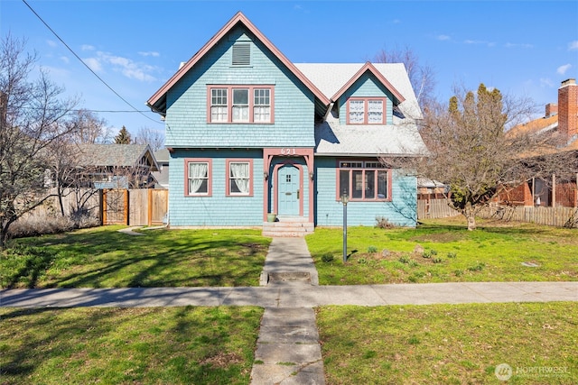 victorian-style house with a front lawn and fence